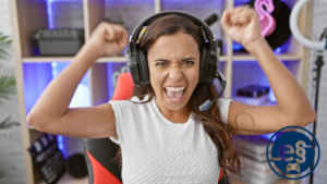 Das Bild zeigt eine Frau mit einem Headset auf dem Kopf, die ihre Arme in die Luft gestreckt hat und sich über ihren Sieg im E-Sport freut.