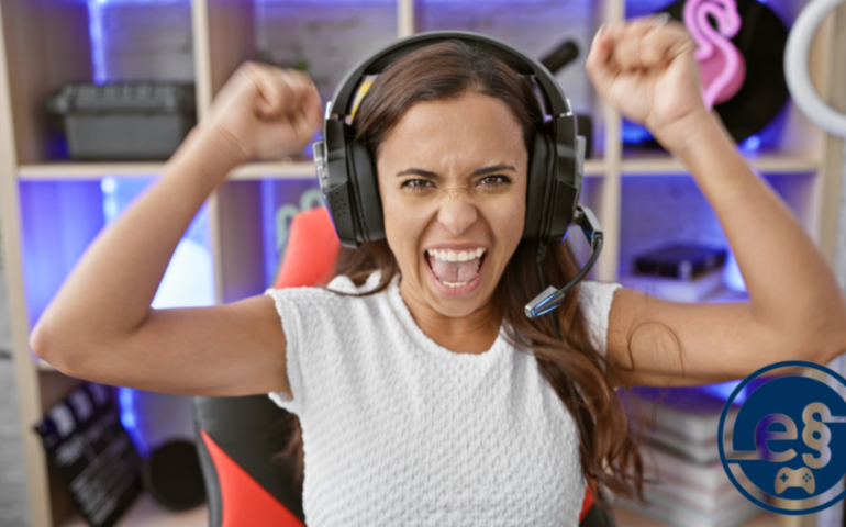 Das Bild zeigt eine Frau mit einem Headset auf dem Kopf, die ihre Arme in die Luft gestreckt hat und sich über ihren Sieg im E-Sport freut.